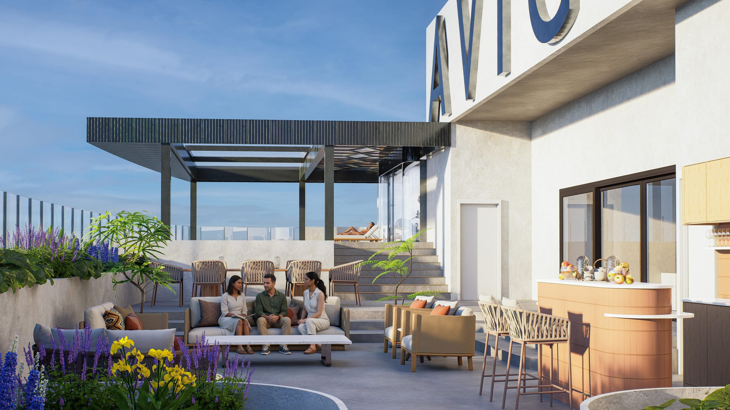 Rooftop lounge with three people talking on a sofa, a curved terracotta bar, dining chairs and steps up to the covered pool deck, below the large AVIGHNA letters.