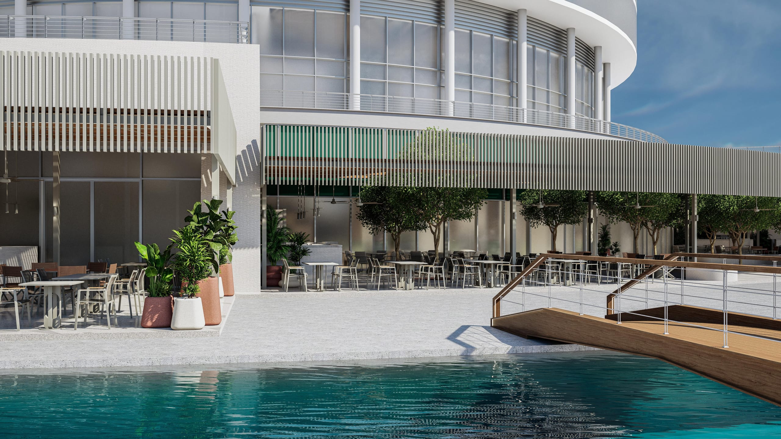 Restaurant terrace at the base of the round building, with a timber footbridge crossing the pool.