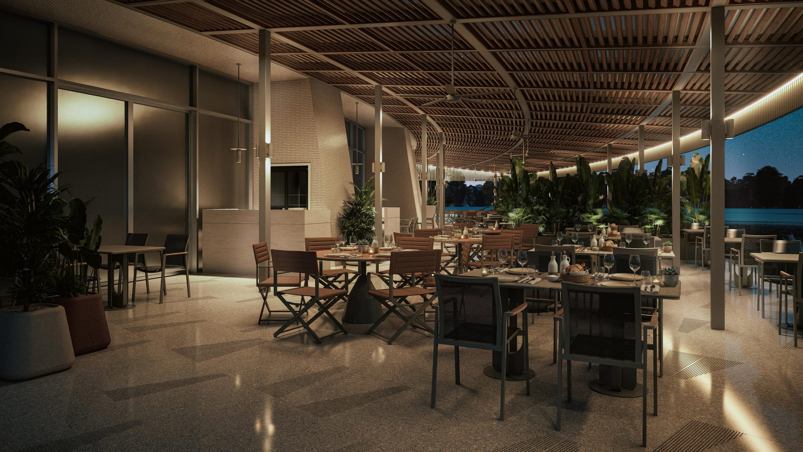 The restaurant terrace at night, lit by wall lights and a line of light along the canopy edge, with the pool beyond.