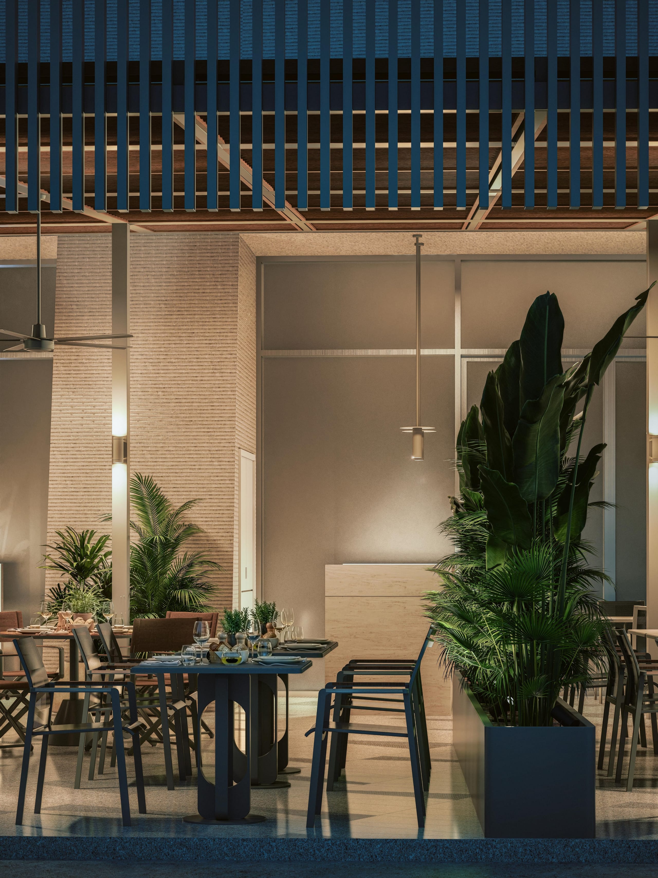 Night view of a table under the lit slatted canopy, with palms in a planter and the bar behind.