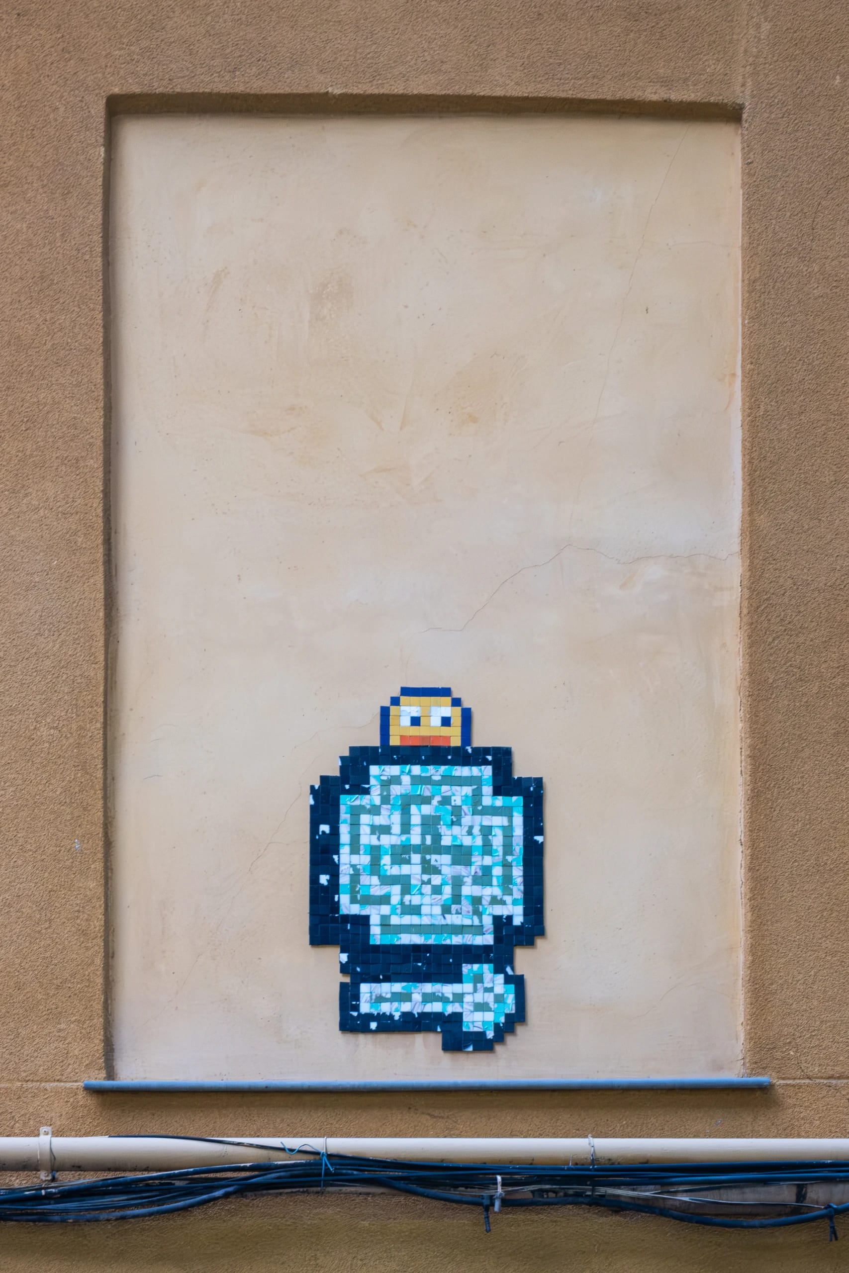 Blue pixel mosaic on a textured street wall