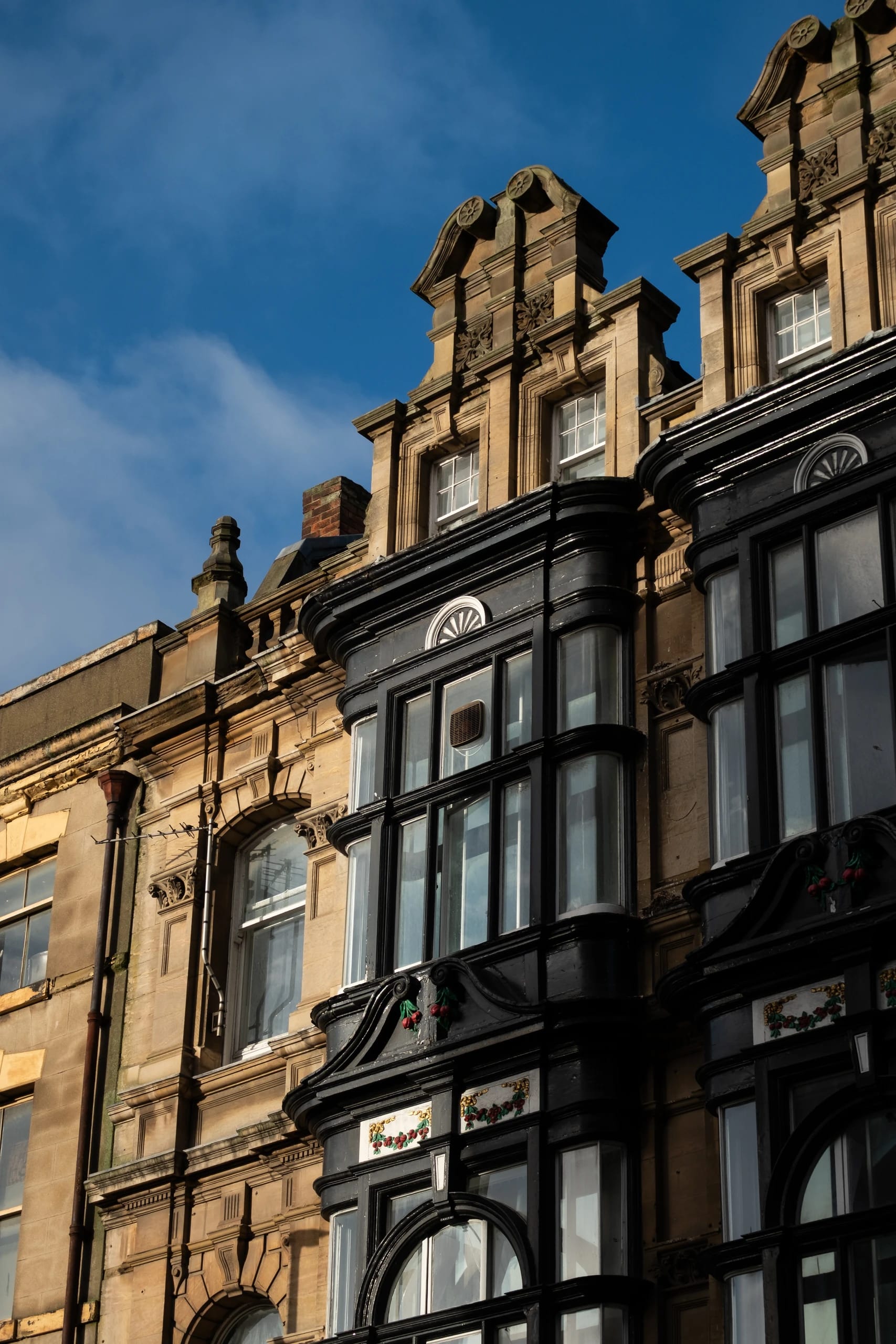 Sunlight across stone gables and dark projecting bay windows
