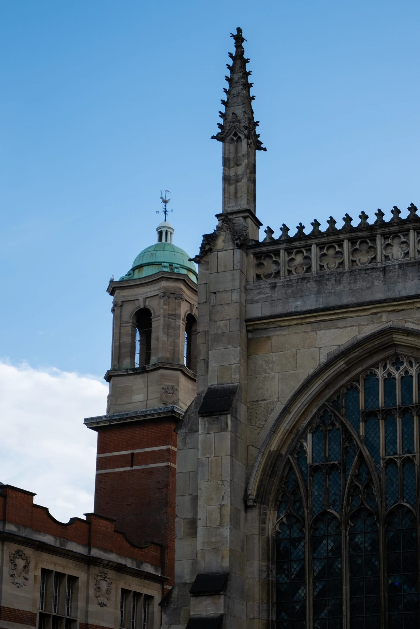 Gothic window tracery and a stone pinnacle beside a copper-domed tower