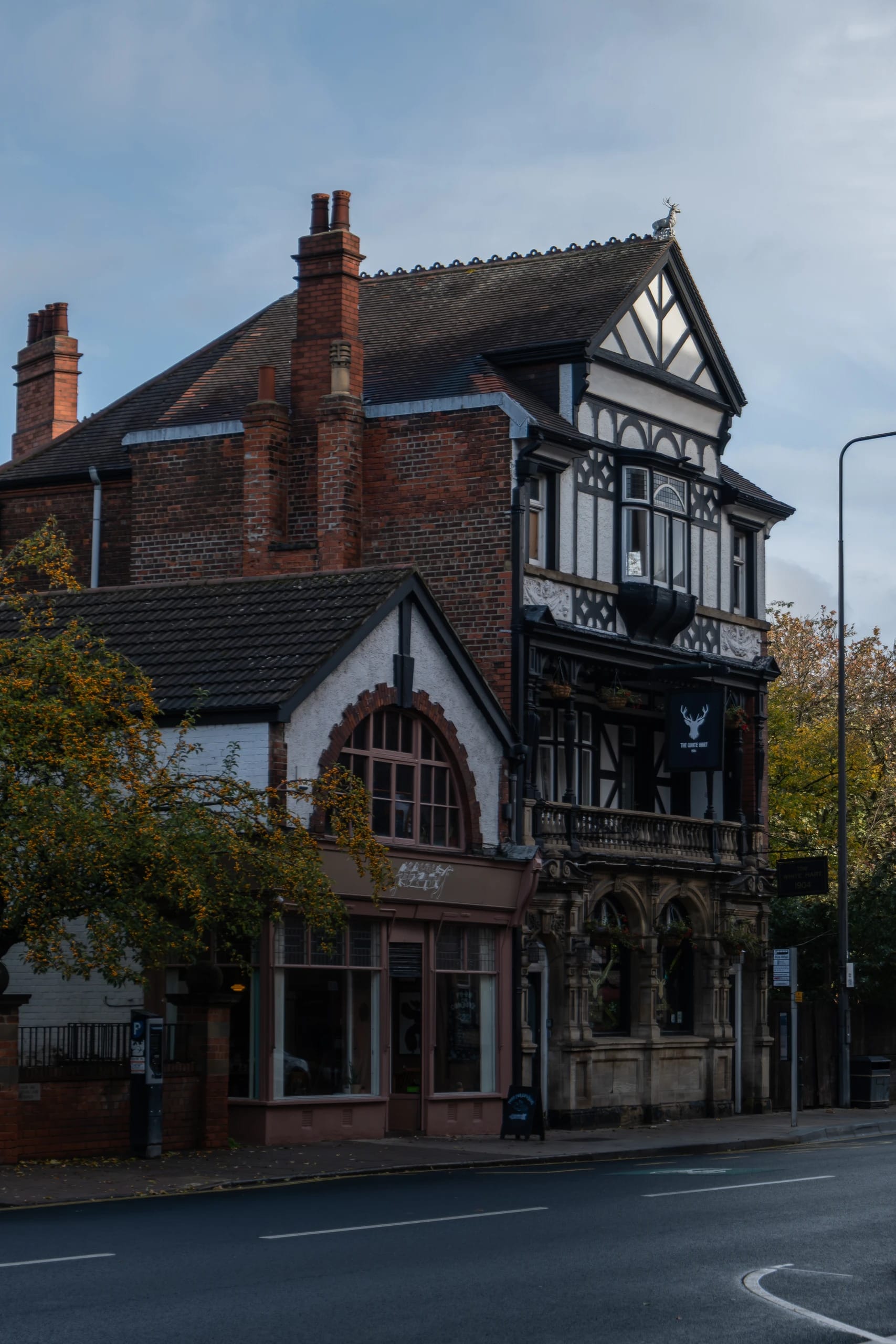 A half-timbered pub facade beside autumn trees