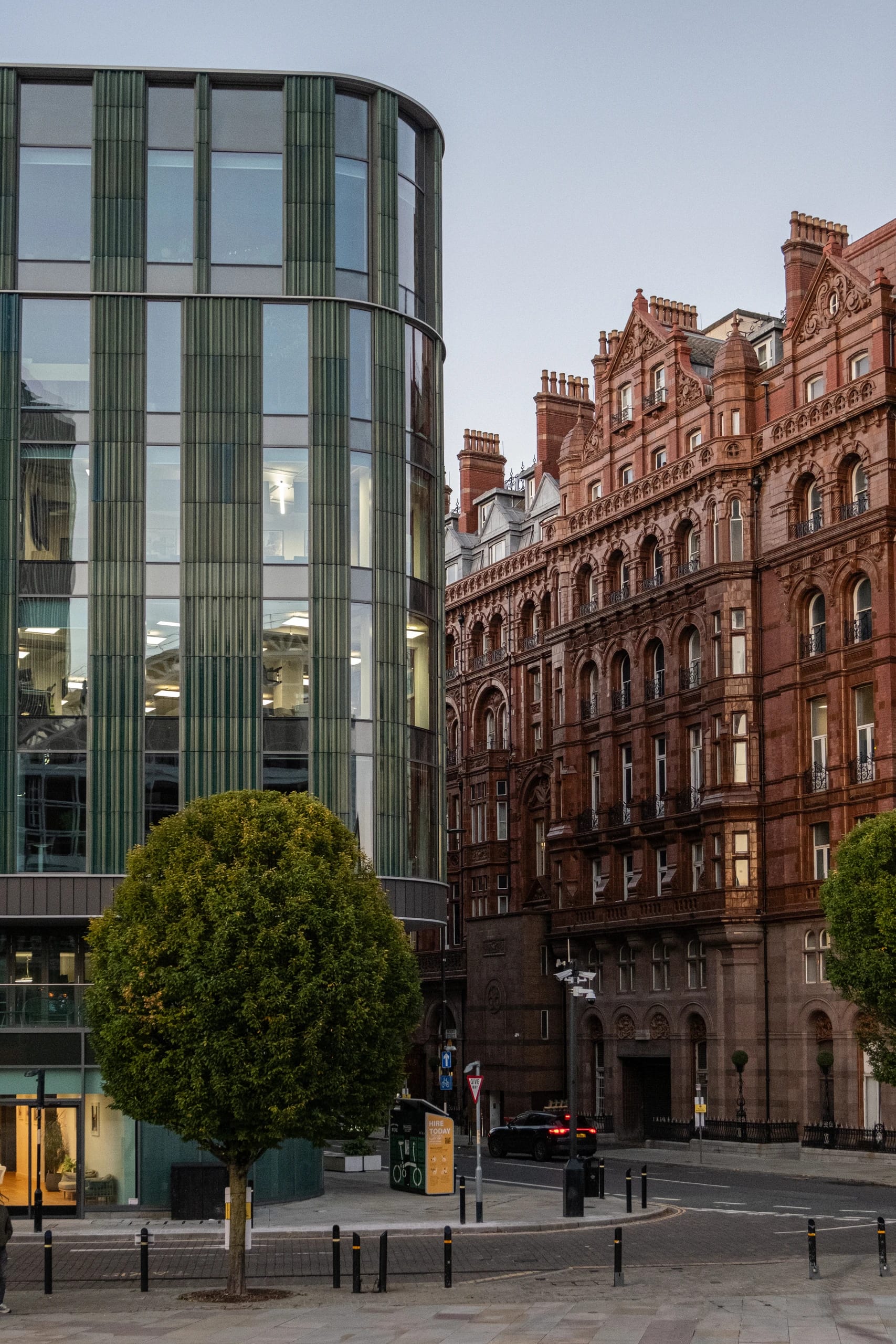Contemporary glass architecture beside the red-brick Midland Hotel