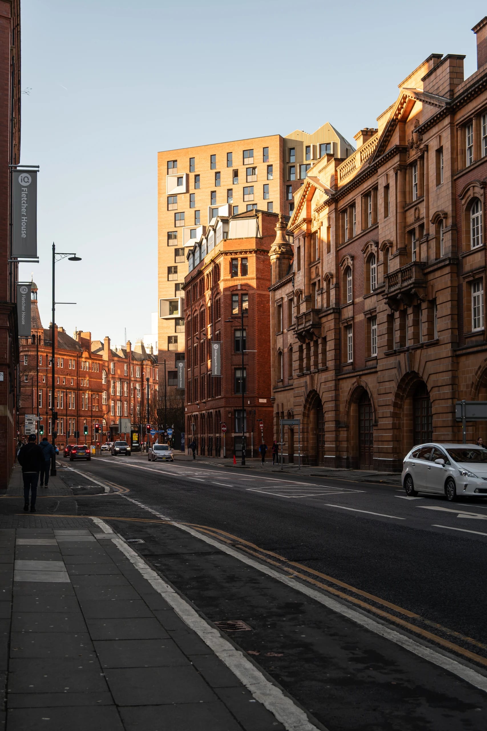 Warm sunlight on historic buildings along a Manchester street