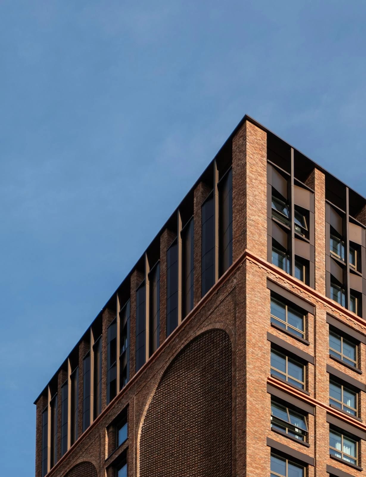 Contemporary brick facade with arched recesses beneath a clear sky