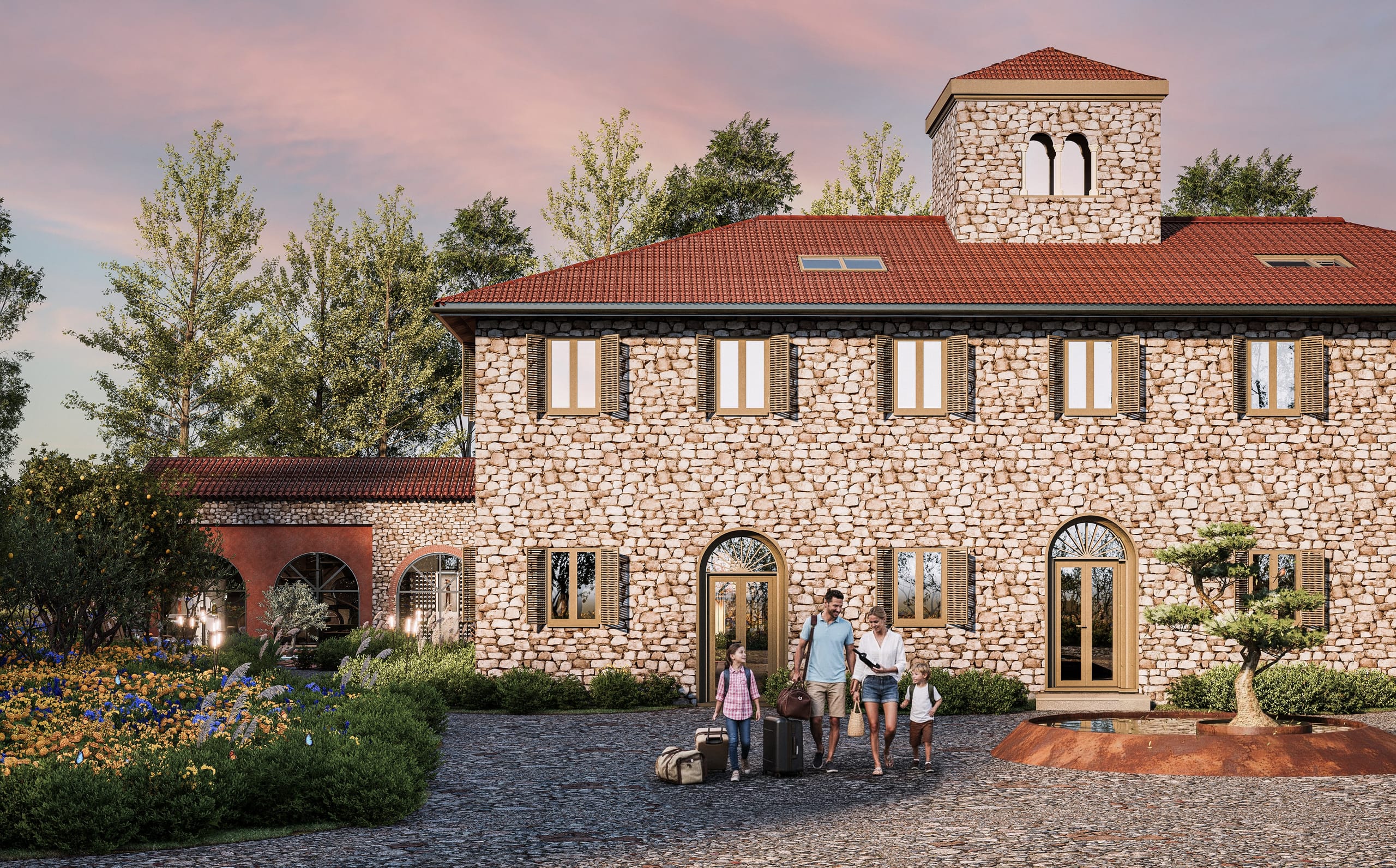 A family arriving with suitcases at the stone manor house with green shutters and a tower, beside a round planted fountain and flowering beds.