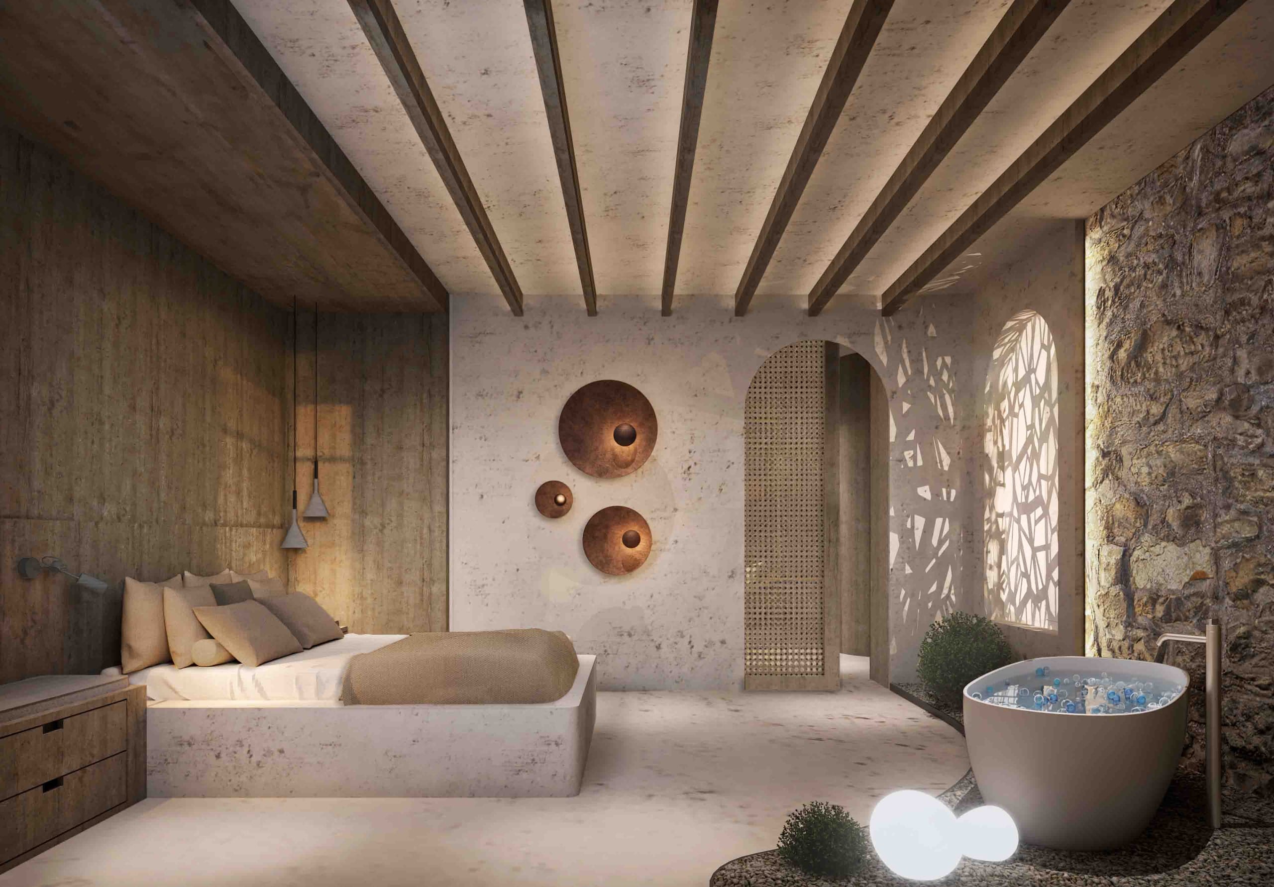 Suite bedroom with timber ceiling beams, a low plastered bed, copper wall lights, a perforated arched screen, a freestanding bath beside a rough stone wall and glowing globe lamps on pebbles.